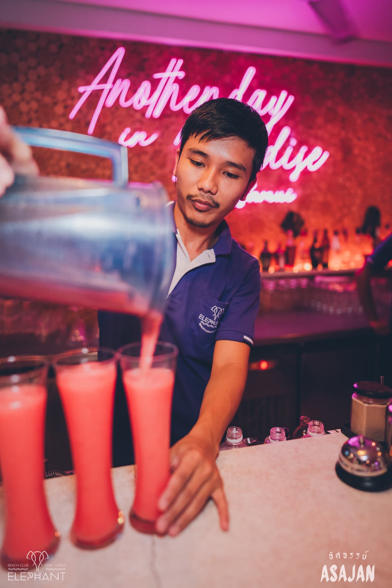 A bartender pouring cocktails under neon light at Elephant Beach Club, Koh Samui