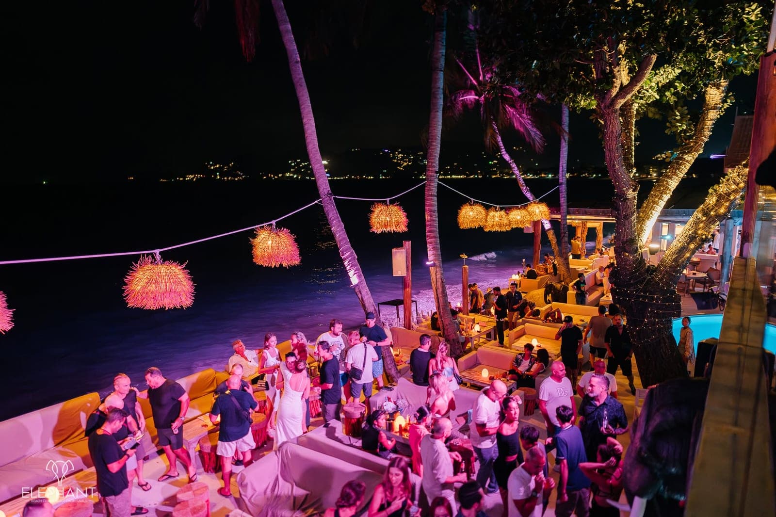 Guests relaxing on shoreline sofas under lantern light during a Saturday night at Elephant Beach Club
