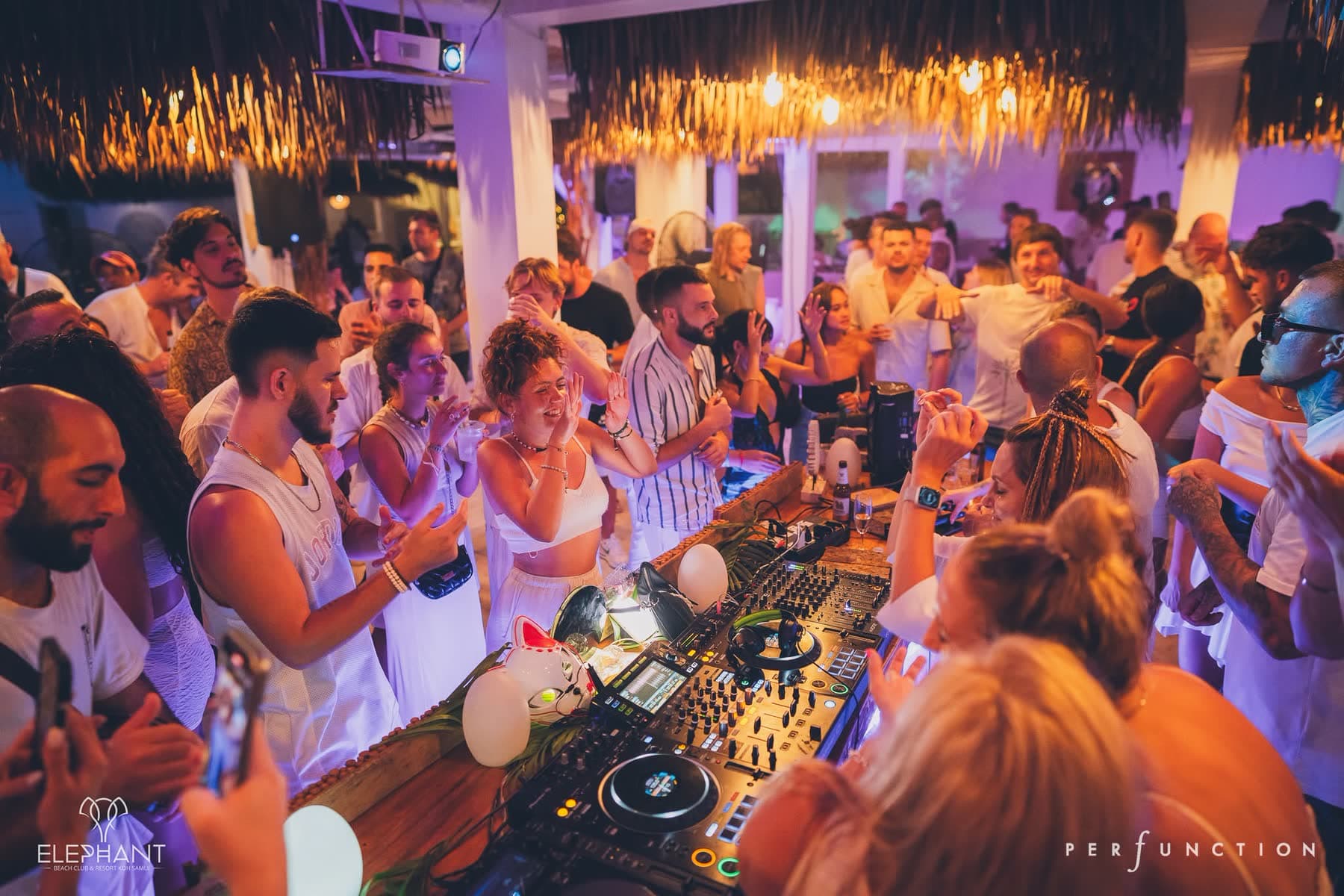 Guests packed around the DJ decks under the thatched roof at Elephant Beach Club, Koh Samui