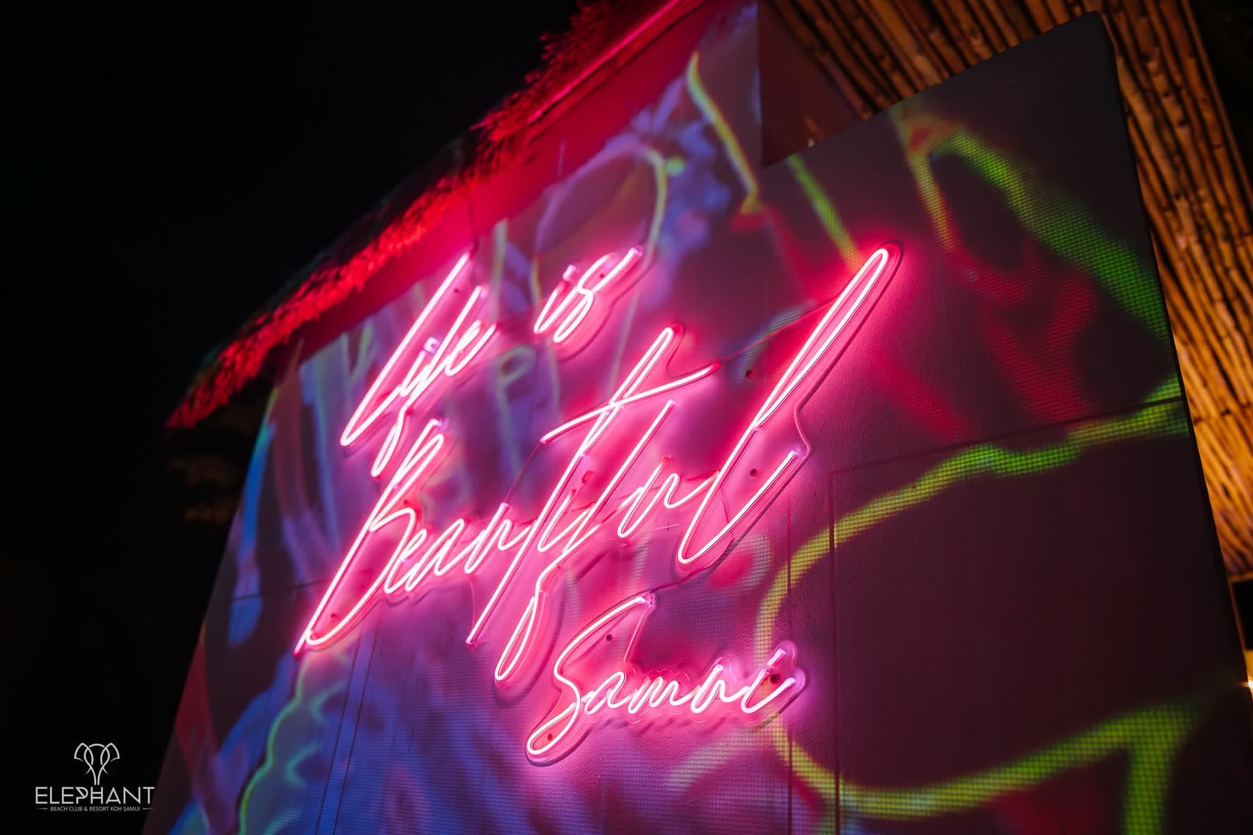 The pink neon sign reading Life is Beautiful Samui glowing on the wall at Elephant Beach Club