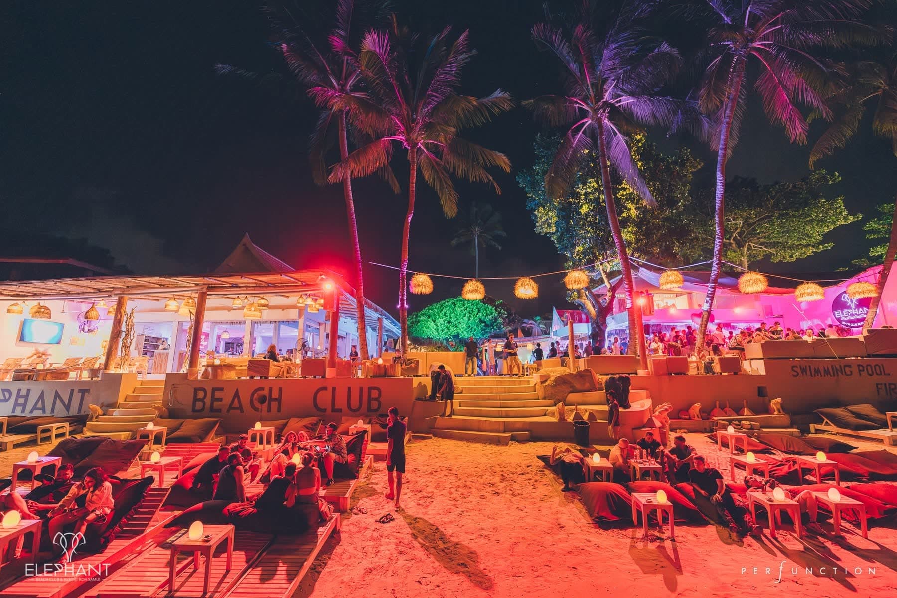The beach club lit in pink at night, sunbeds on the sand below the painted BEACH CLUB sign, Chaweng Beach