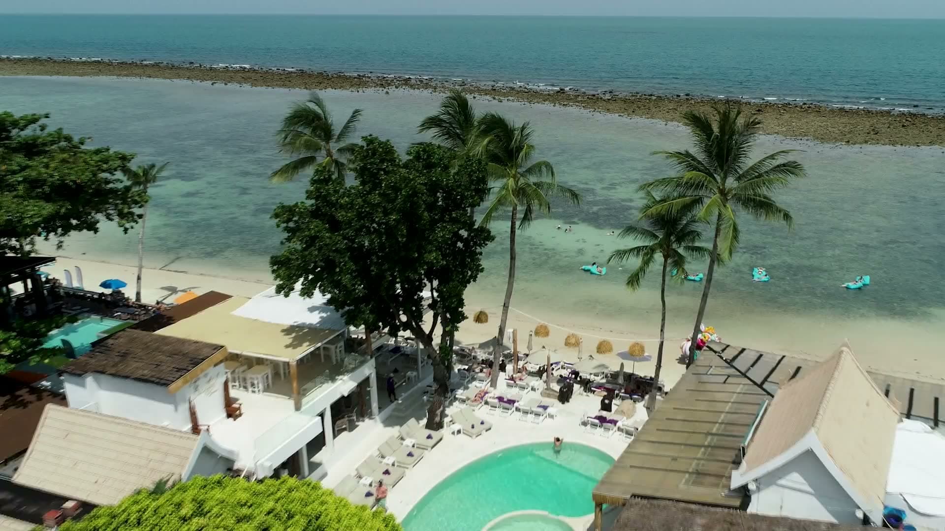 Aerial view of Elephant Beach Club on Chaweng Beach, Koh Samui: the pool, sunbeds under the palms and the reef flat beyond