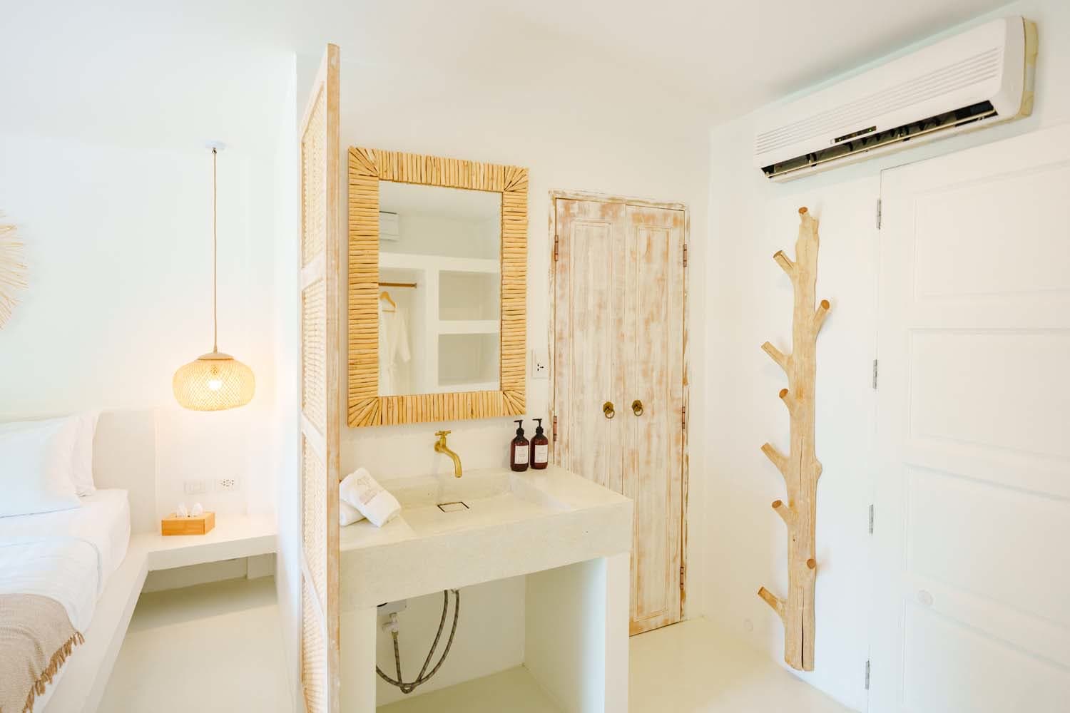 Bathroom vanity with a round mirror, gold tap and wardrobe in the Deluxe Bungalow