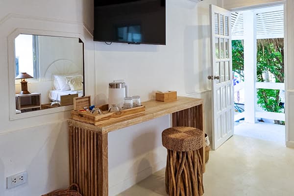 Console desk with a flat-screen TV and the door open onto the garden in the Robinson Bungalow