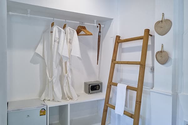 Wardrobe with bathrobes, an in-room safe and bamboo towel ladder inside the Robinson Bungalow