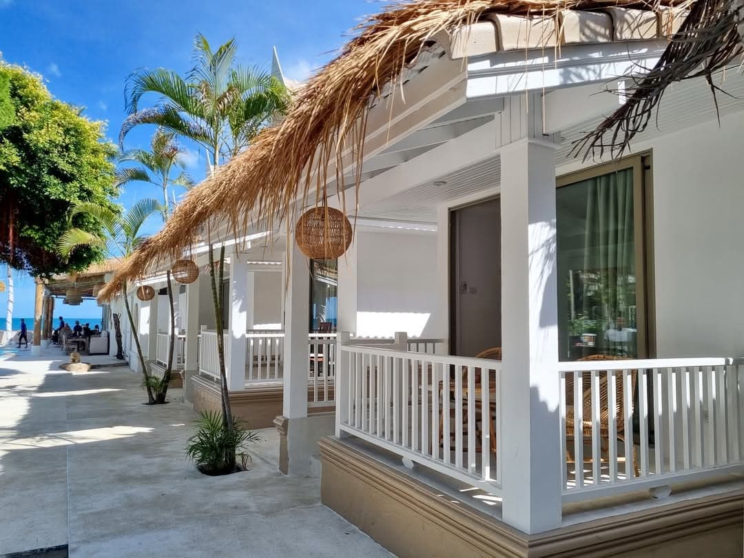 Row of white bungalow verandas under thatched roofs and rattan lanterns at Elephant Beach Resort, Chaweng Beach, Koh Samui