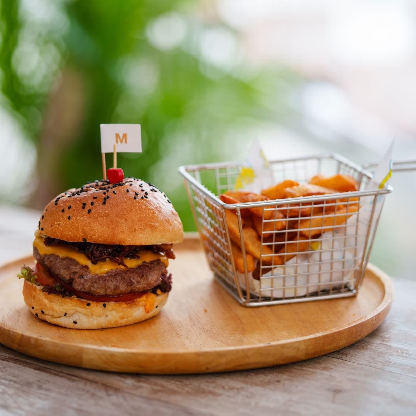 Mini cheeseburger with a wire basket of fries on a wooden board at Elephant beachfront restaurant