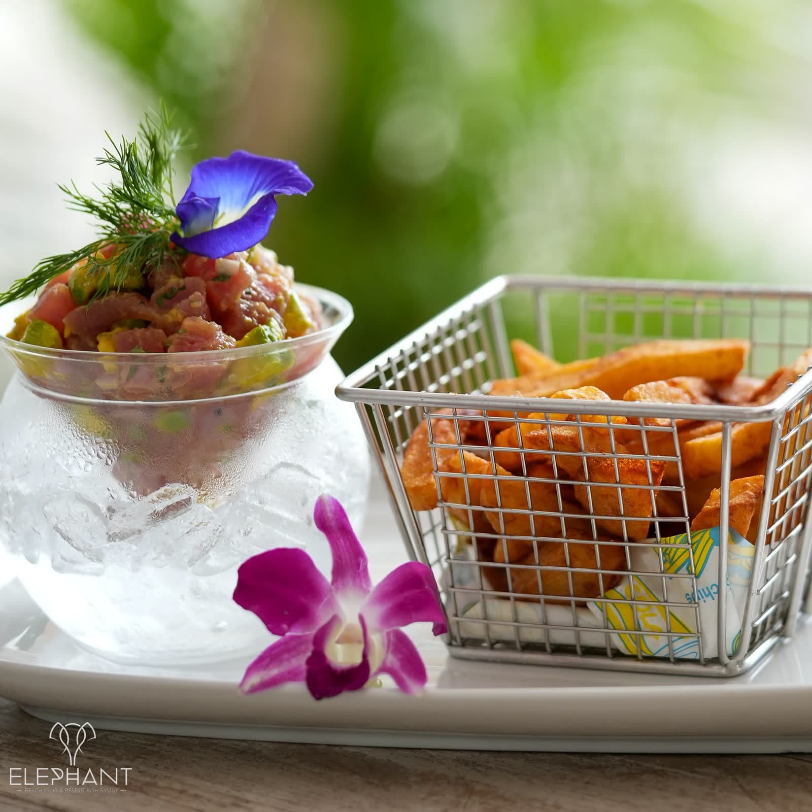 Tuna tartare served in a glass over crushed ice with a basket of fries at Elephant beachfront restaurant